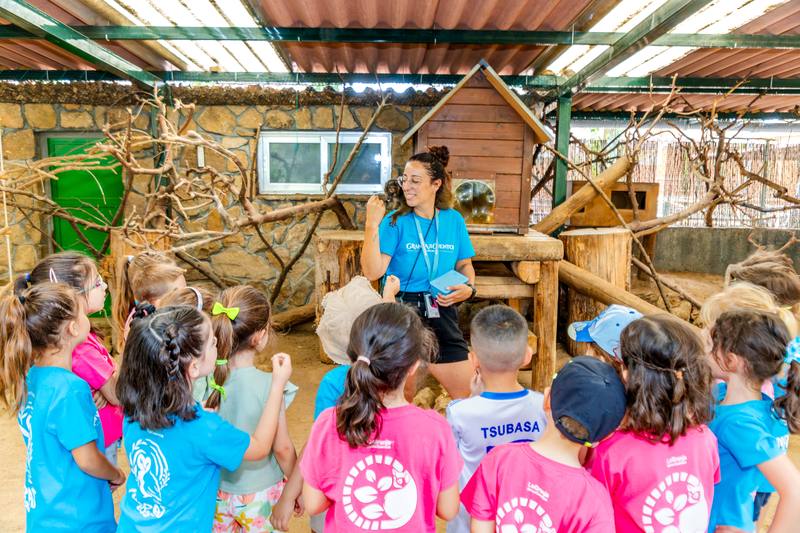 Una monitora enseña a un grupo de escolares el interior de un aula de naturaleza tropical.