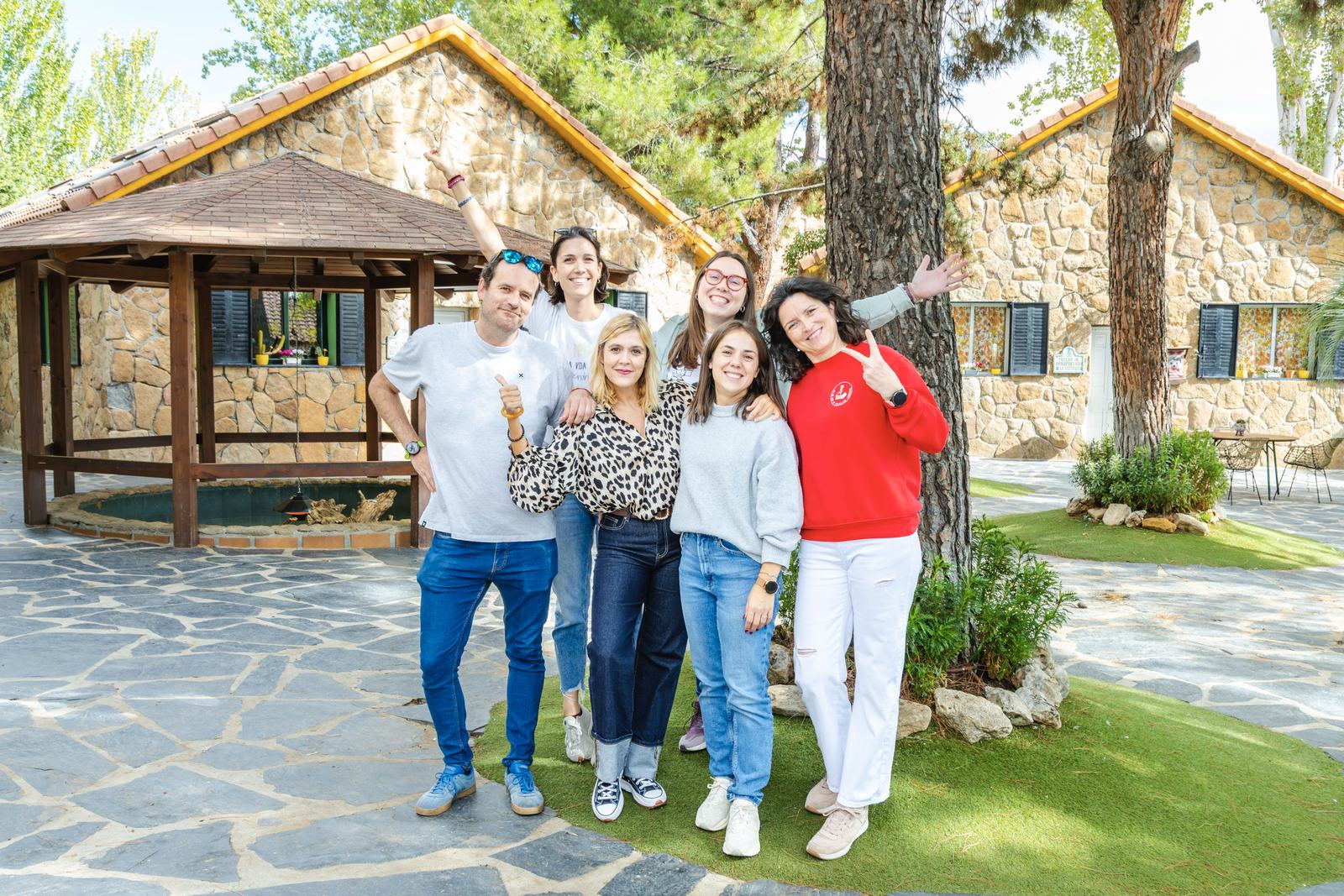 El equipo de La Granja de los Cuentos posa sonriente en la plaza empedrada, junto a las casitas de piedra.