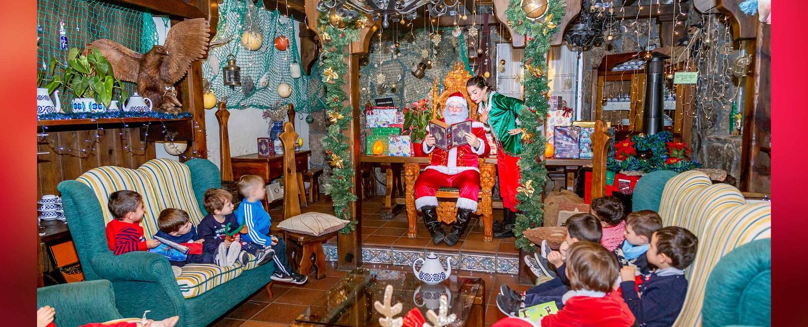 Un grupo de escolares sentados en los sillones de la casa de Papá Noel, escuchándole junto a la chimenea.