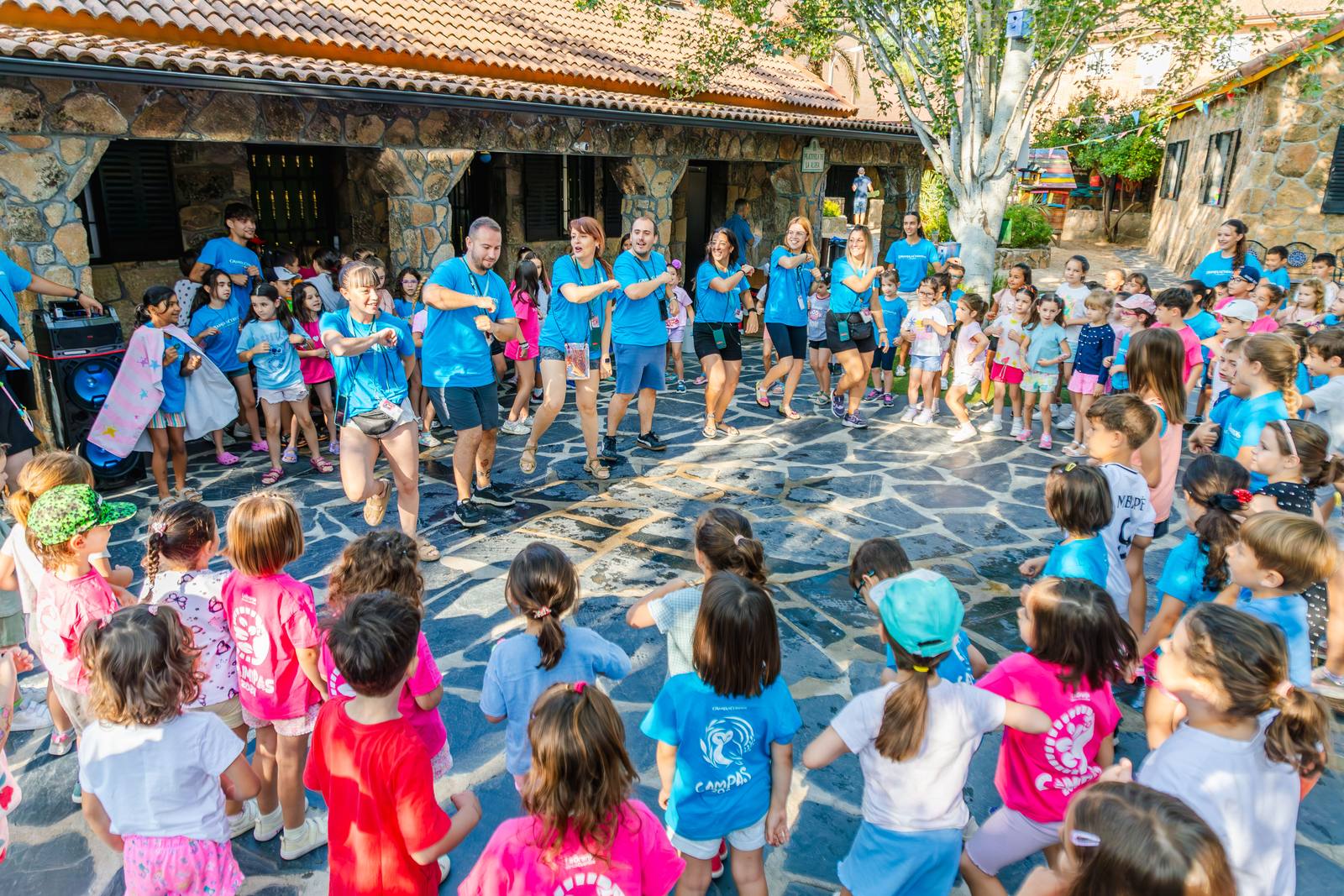 Decenas de niños reunidos en círculo en la plaza empedrada de La Granja de los Cuentos.
