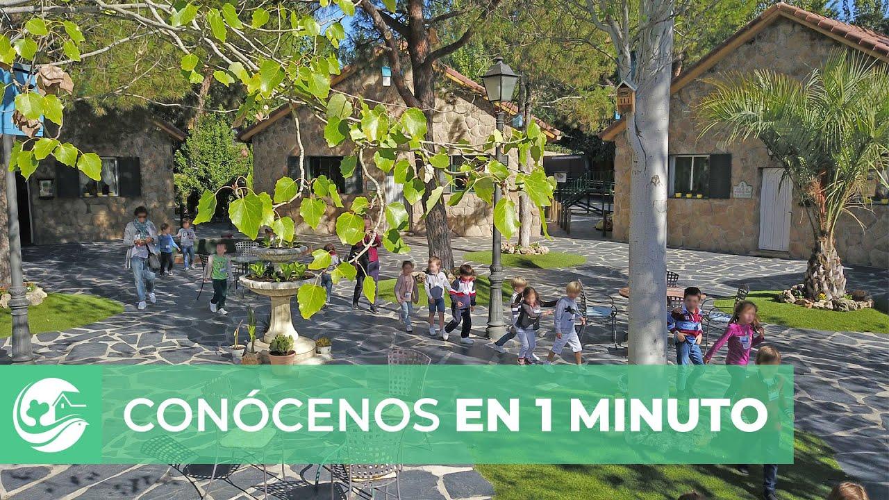 La plaza empedrada de La Granja de los Cuentos con las casitas de piedra y un grupo de escolares cruzándola.